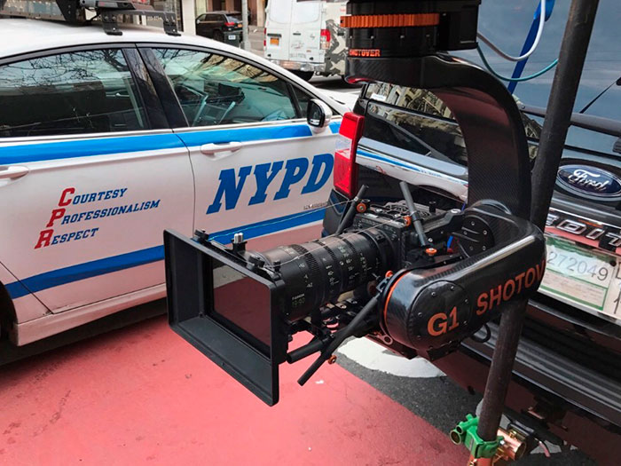 Garage with a NYPD police cruiser and a black SUV with SHOTOVER mobile camera system mounted on the back