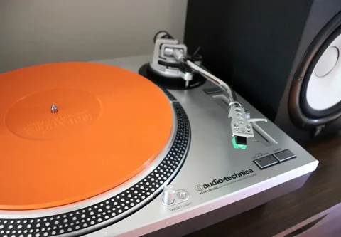 Turntable with orange vibration absorbing mat where the record sits.