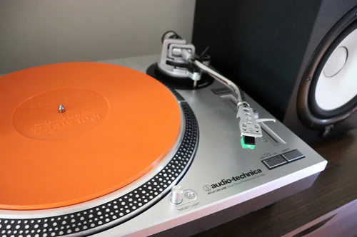 Turntable with orange vibration absorbing mat where the record sits.