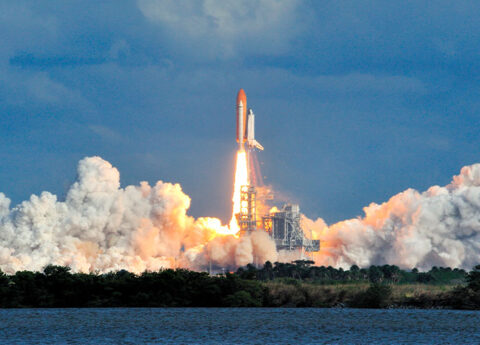 NASA space shuttle launching off into the blue sky at Cape Canaveral