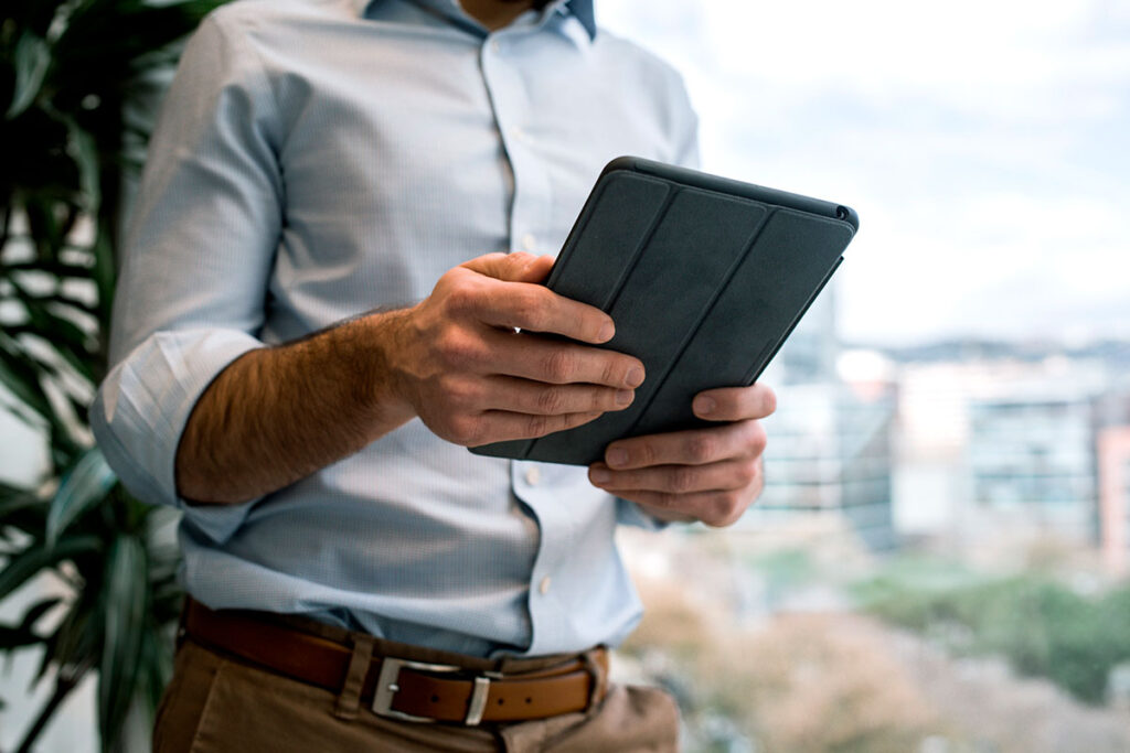 An image of a man's torso who is holding an electronic tablet device.