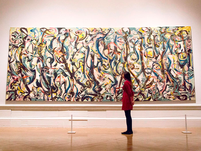 Jackson Pollock's "Mural" in the Getty Museum with an admiring patron in a red dress in front.